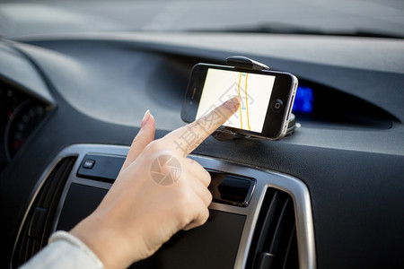 使用带有全球定位系统导航的触摸屏智能手机的女驾驶员图片