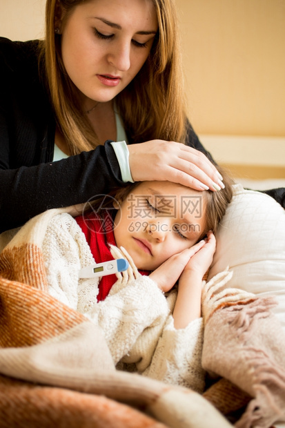 年轻担忧的母亲肖像检查生病女儿的温度图片