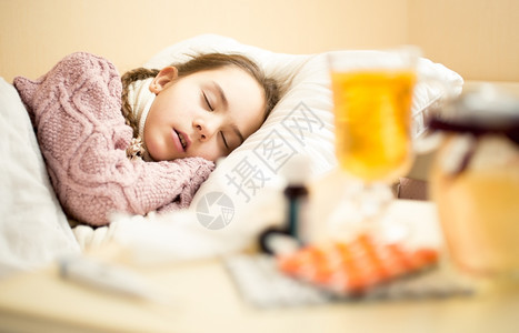穿着毛衣睡在床上的小生病女孩肖像图片