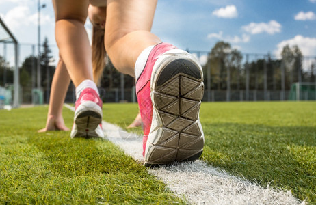 穿着运动鞋站在草地上白线的色运动鞋妇女近距离拍摄图片