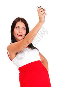 年轻快乐的有吸引力穿红裙子女使用手机拍摄照片图片
