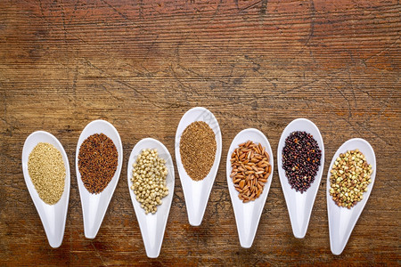 7个健康无谷质的物quinoa棕米amaranthteffhuckwheatsorghumkaniwa小勺子与生锈木对面的顶层视图片