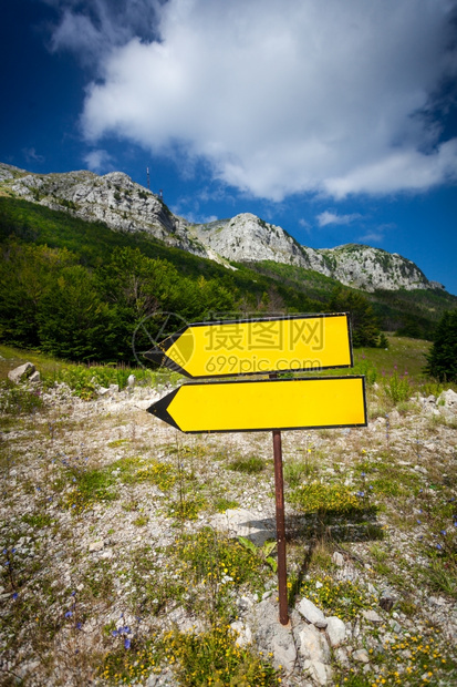 黄标牌站立在通往高山的路上图片