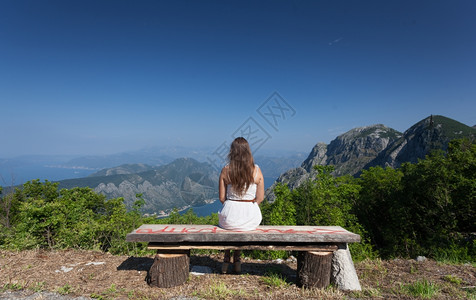 坐在高山长椅上的美丽黑发女背景图片