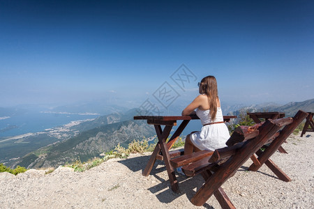 美丽的女人坐在山顶长椅上看着风景图片