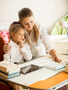 年轻母亲在运动书上指年轻母亲向女儿解释家庭作业图片