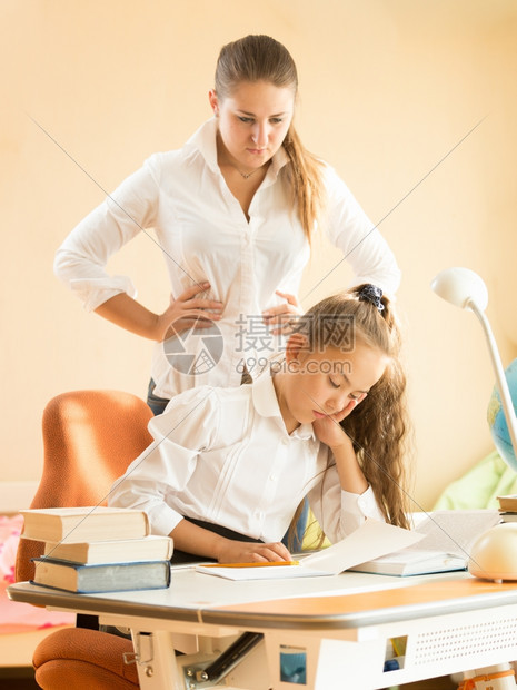 年轻母亲生女儿在做功课时书桌上睡觉的愤怒图片