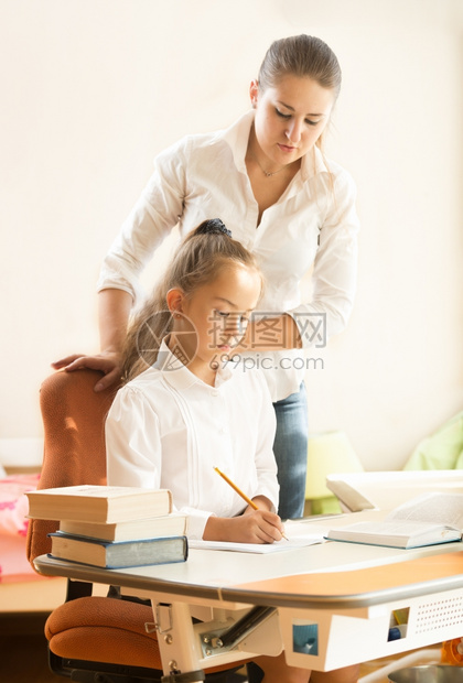 可爱的女学生做功课而母亲看着她图片