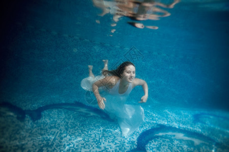 身着白衣服的年轻女子上水面游泳池的图片