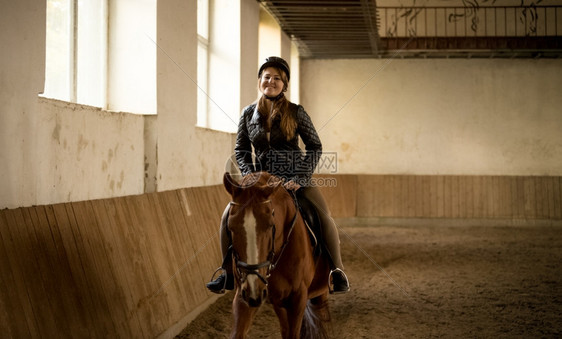 女人的肖像骑着美丽的棕色马在室内场图片
