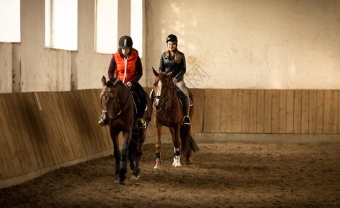 两名女骑师在马厅受训的室内镜头图片