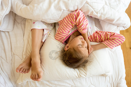 小女孩和姐妹在床上枕头脚踩的肖像图片