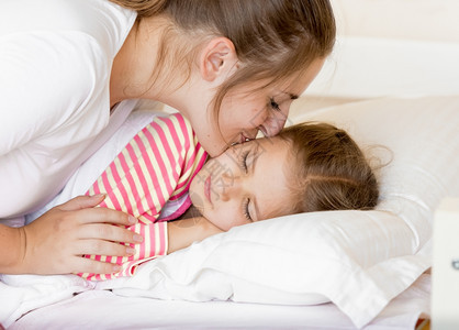 年轻母亲早上吻睡着女儿的肖像图片