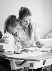 快乐母亲和女儿做功课的单色肖像图片