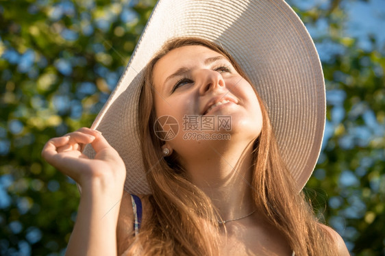 戴着白帽子看太阳微笑的黑发女人近视肖像图片