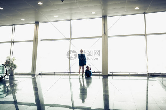 女子站在候机楼等待登机图片