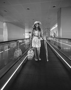 戴帽子的美女站在机场扶梯上微笑的看着镜头图片