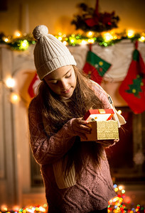 穿着毛衣的可爱小女孩在圣诞节前夕礼物盒里看图片