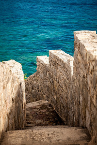 美丽的古石墙有通往蓝海的楼梯图片