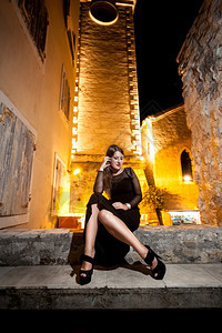 穿着长裙的漂亮迷人女坐在街上晚的石凳图片