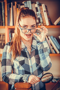 图书馆的嬉皮女学生戴眼镜的女子拿着放大镜图片