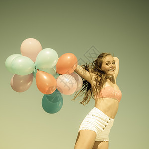 暑假庆祝活动和生方式概念具有吸引力的体育女运动少在海滩上用彩色气球跳出海滩老旧的回春调图片