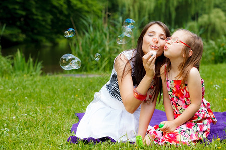 母亲和女儿的小孩在公园一起吹泡泡图片