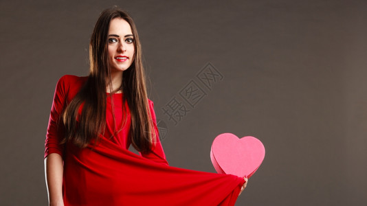 情人节爱浪漫概念红裙子的长发女美拿着心形礼物盒深灰色背景背景图片