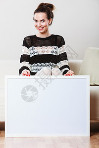 广告概念时尚女坐在沙发上用空白的演示板展横幅标志的女模型在广告牌上签名复制文本空间图片