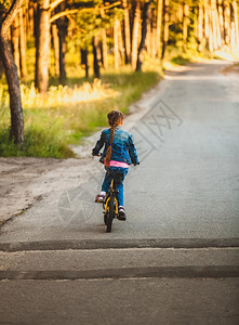 女孩在森林骑黄色自行车的照片图片