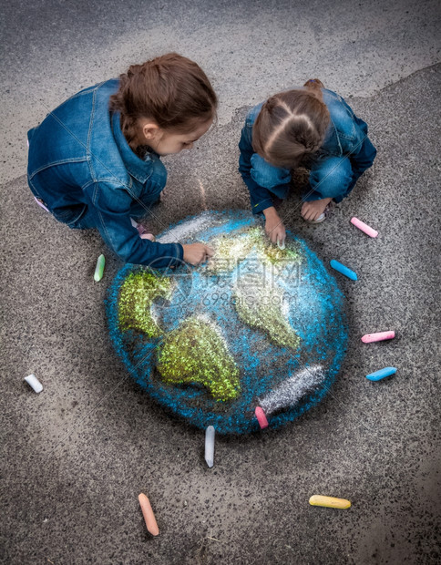 两名女孩在地面上用粉笔绘制符合现实的地球图像图片