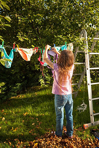 年轻女孩在花园的衣着上挂服图片