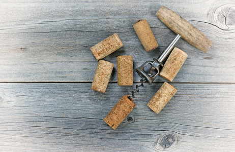 古老的概念是在生锈木制板上有几种用过的葡萄酒软木和开瓶器背景