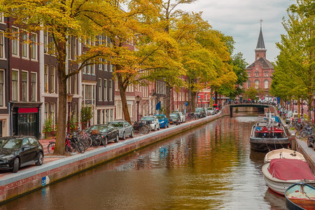 荷兰阿姆斯特丹运河教堂和典型房屋船只和自行车的城市景象图片