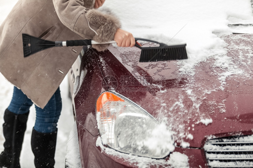 妇女拿着刷子和清理汽车积雪的近照图片