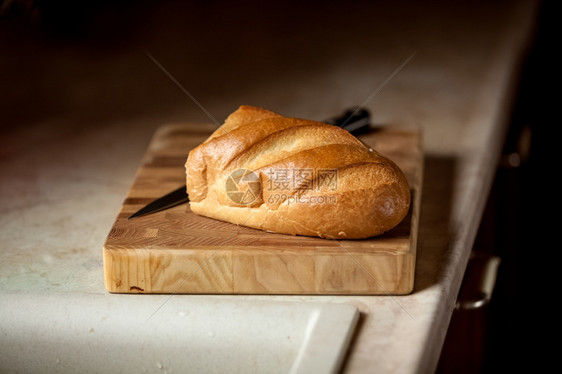 木制桌上面包和刀子的近照片图片