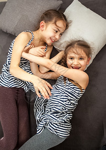 两个年轻姐妹的肖像互相推在床上图片