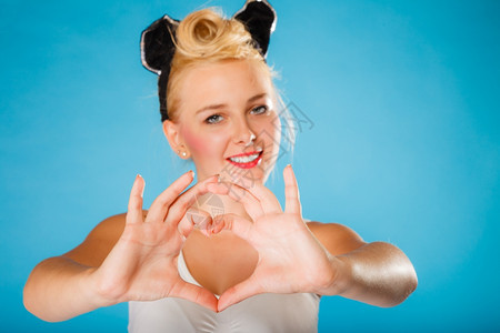 情人节微笑的年轻女人发型在蓝背景上做手心符号图片
