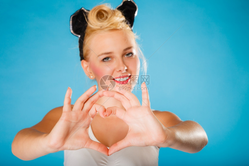 情人节微笑的年轻女人发型在蓝背景上做手心符号图片