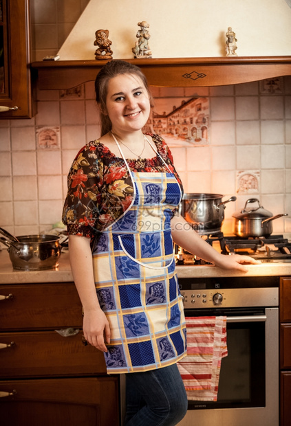 美丽的家庭主妇肖像假扮成配着酱盆的煤气炉子