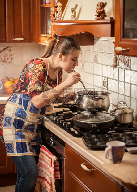 穿着围裙的美女用厨房勺子煮汤
