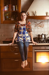美丽的微笑女士坐在桌面上烤炉中烘图片