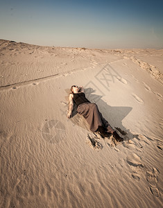 穿着裙子的漂亮女人躺在沙漠丘上图片
