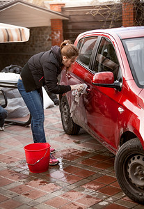 美女在户外用毛巾清洗红色汽车图片