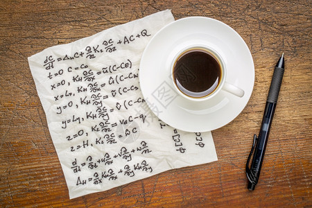 物理学的数方程式在餐巾纸上笔迹在生锈的木制桌子上加一杯咖啡图片