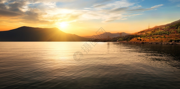 美丽夕阳的平静海和山岳图片