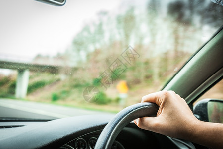 男子手握着汽车和道路方向盘图片