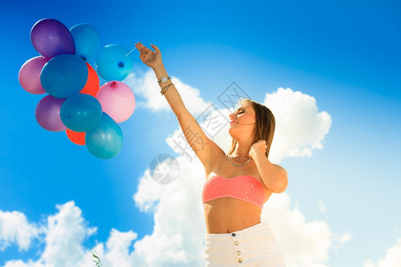 暑假庆祝活动和生方式概念吸引有力的少女孩在海滩蓝天空背景上外面有彩色气球图片