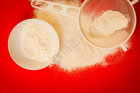 烹饪概念准备烘烤原料和烹饪工具以做蛋糕在红非扁片硅垫子上筛选面粉最高视图图片