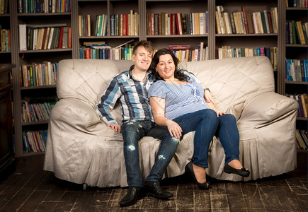 快乐的孕妇和丈夫在客厅的沙发上摆姿势图片
